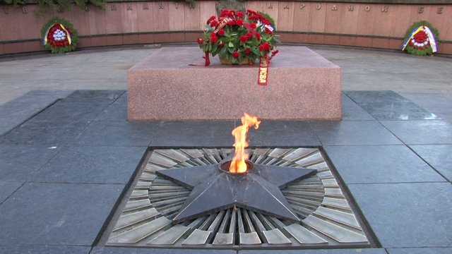 Eternal flame with wreath of flowers at the monument