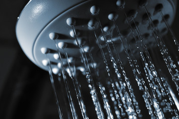 Naklejka na ściany i meble closeup view of water flowing out of shower in dark