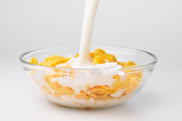 Obraz na płótnie Canvas milk stream flowing to the bowl with corn flakes