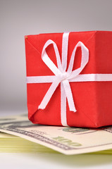 red gift box on the bacth of dollars notes