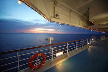 view from deck of cruise ship. sunset. row of lamps. lifebuoy.