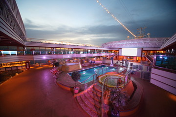 Overview of deck of cruise ship with screen, pool and baths