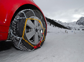 Autoreifen mit Schneekette auf Schneefahrbahn
