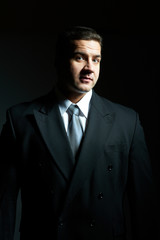 Dark portrait of handsome stylish young man in black suit