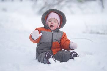 Fototapeta na wymiar cute baby sit on fresh snow in park