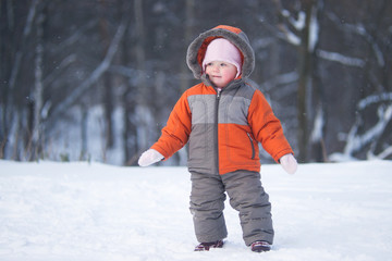 Fototapeta na wymiar cute baby stay in deep snow and look to side in park