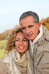Happy couple walking in country field in autumn