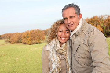 Happy couple walking in country field in autumn