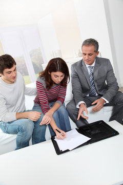 Young couple sigining renting contract with real estate agent