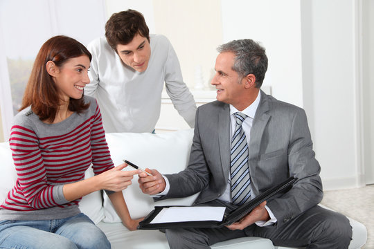 Young couple sigining renting contract with real estate agent