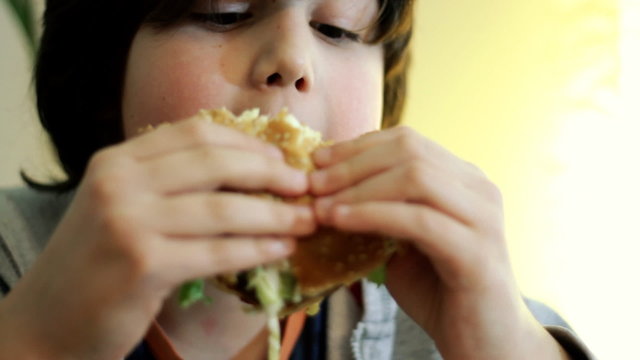 Young boy eating hamburger