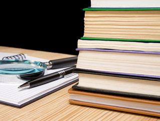pile of book and pen on notebook on black