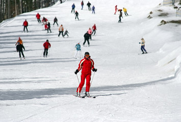 Fototapeta na wymiar Female skier skiing down a wide track for beginners