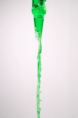 Green liquid pouring out of a glass bottle