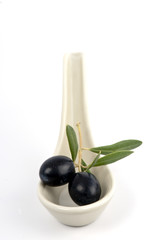 Two freshly picked black olives with a few leaves in a ceramic s