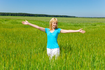 Naklejka na ściany i meble The happy young woman in the field of green ears