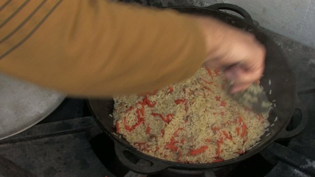 Stirring pilaf with kitchen spoon, Closeup