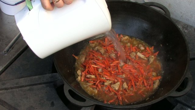 Adding hot boiled water to Pilaf ingredients in Wok, Closeup