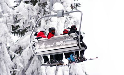 Skiers on a ski-lift. One skier waving his hand.