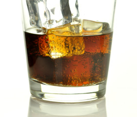 glass of cola with ice cubes close up