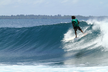 Surfer riding fast on tropical blue wave