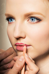 Portrait of a woman putting on lip liner.