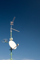antennas and a satellite dish on a roof  against lovely blue sky © lightpoet