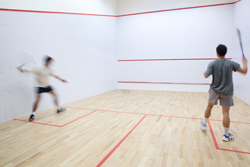 Squash players in action on a squash court (motion blurred image