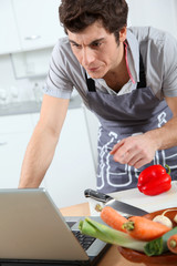 Man in kitchen looking at recipe on internet