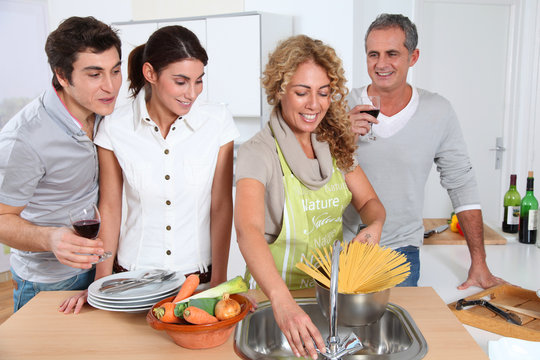 Group Of Friends Prepraing Dinner In Home Kitchen