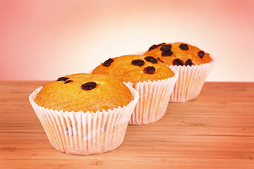 Muffins with raisins on wooden surface isolated on white