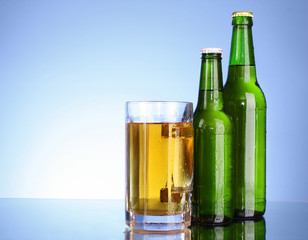 Bottles with beer and cup on blue background
