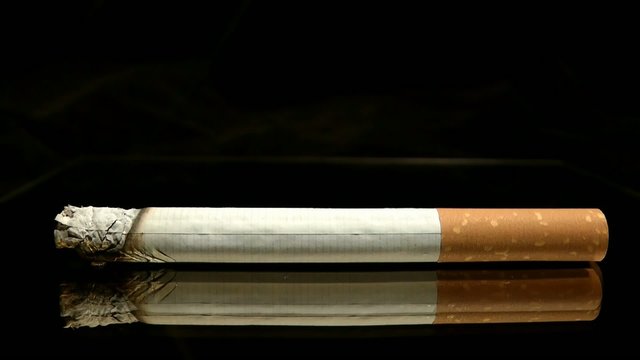 Zigarette mit seitlicher Ansicht brennt im Zeitraffer ab