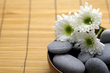 Bowl of pebbles with Chrysanthemums flowers on mat