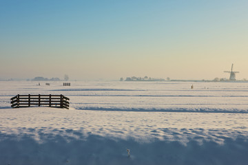 Obraz premium Frozen farmland with windmill in background
