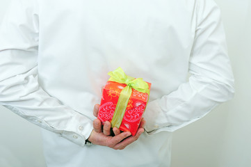 Geschenk hinterm Rücken versteckt