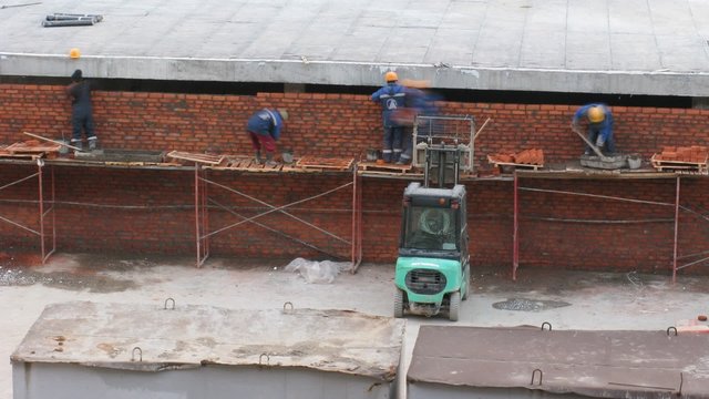Workers build a wall of a brick, a building site