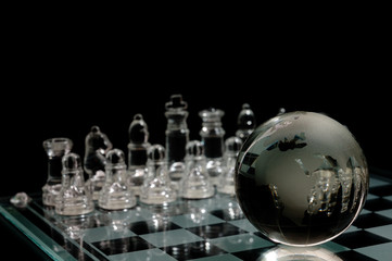 Crystal chess pieces with a globe in black  background.