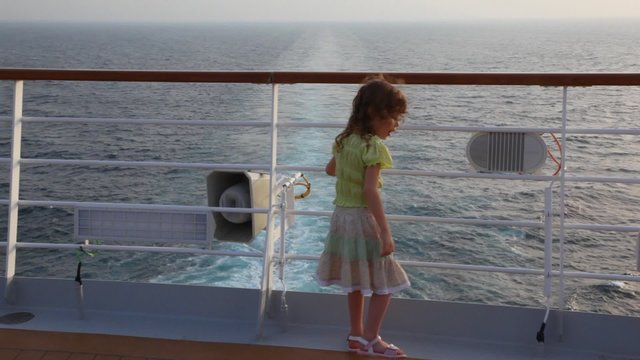 girl stands aft of cruise liner and looks at sea