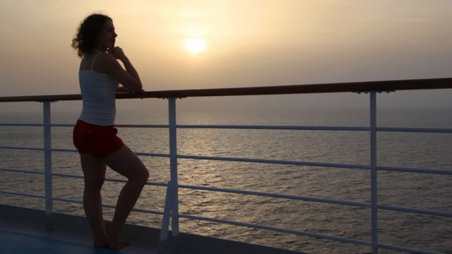 woman stand on deck of cruise ship and looks at sea