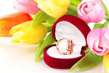 wedding rings and flower bouquet on white