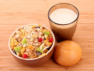 muesli, milk and bun on wooden surface isolated on white