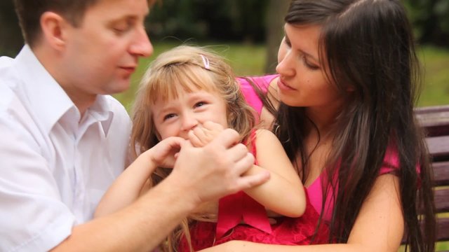 couple and their daughter play game with fingers in park