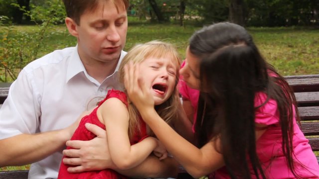 couple embraces their crying daughter and try to calm her