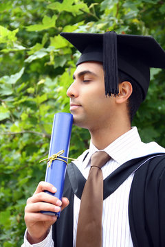 A portrait of a young Indian guy in a graduation gown.