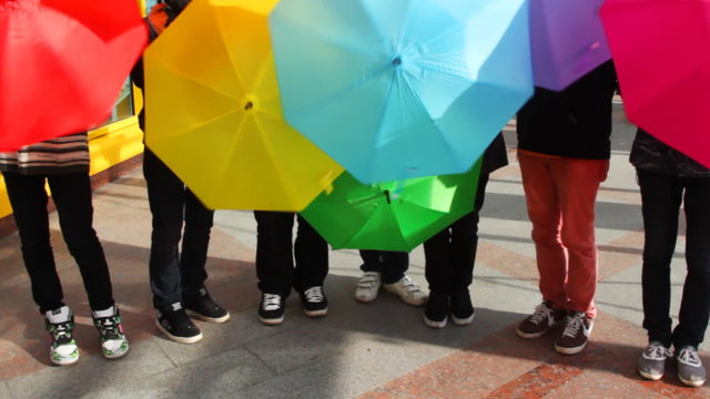 men twist colored umbrellas on bridge