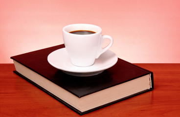 Fototapeta na wymiar Perfect cup of black coffee on the book in hard cover on a woode