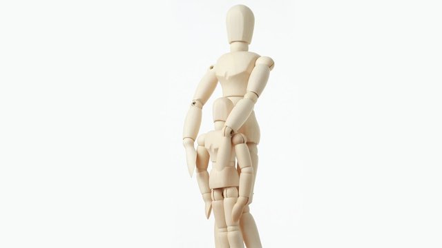 wooden figures of parent embracing his child from back