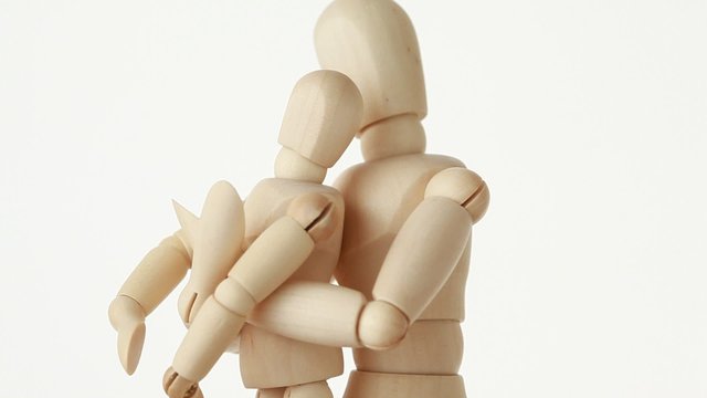 wooden figure of parent embracing his child, half body