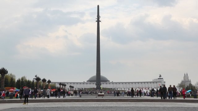 people walks near obelisk in Poklonnaya Hill monument